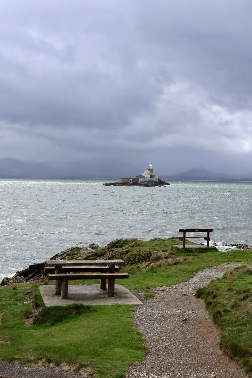 Picnic bench on the grass above the shore at Fenit, looking out at Little Samphire lighthouse