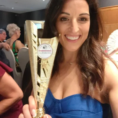 Zhaia founder, smiling woman holding a trophy. Wild Atlantic Aways event. The founder is wearing a blue dress. The trophy is gold with a logo.